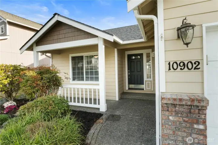 Inviting covered entry with, charming porch, and well-kept landscaping that welcomes you home.