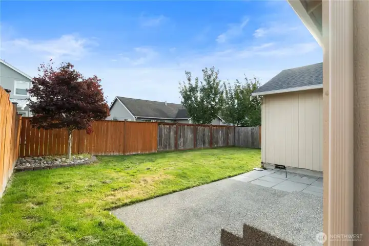 Fully fenced backyard with a spacious patio, lush lawn, and mature landscaping—ideal for outdoor dining, play, or simply unwinding in privacy.