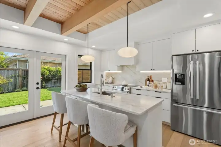 Custom-designed kitchen with large island, full height natural stone backsplash, and under-cabinet lighting.  Microwave and dishwasher in island.  Tons of natural light make this space perfect for relaxing or entertaining.