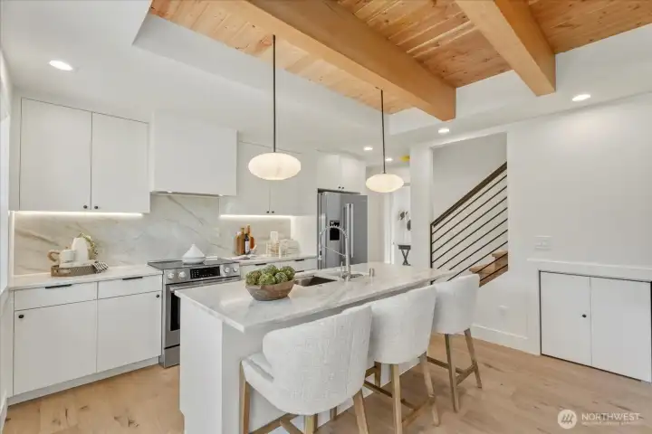 Custom-designed kitchen with large island, full height natural stone backsplash, and under-cabinet lighting.  Microwave and dishwasher in island.  Tons of natural light make this space perfect for relaxing or entertaining.