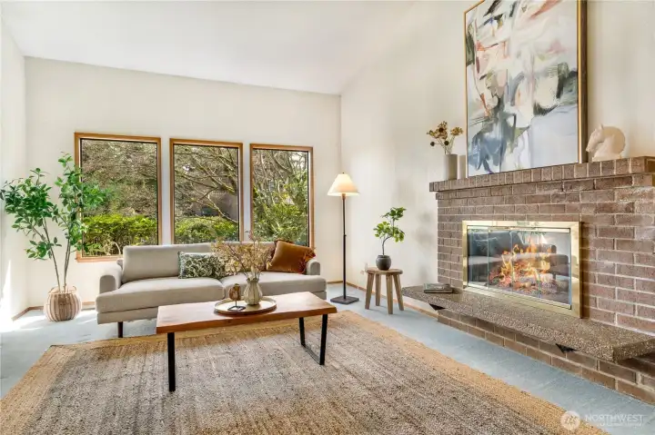 A beautiful living room centered around a warm brick fireplace, accented by rich beam details and an effortless flow into the dining room—perfect for gathering, celebrating, and hosting unforgettable holiday moments.
