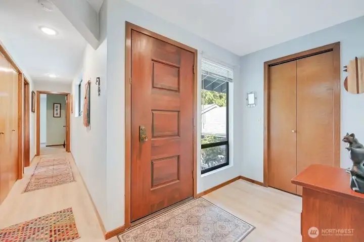 The welcoming entry, with the front door in the center, a coat/storage/hot water tank closet is on the right, and the hallway on the left leads to two guest bedrooms, a full bath, and the laundry closet with washer & dryer.