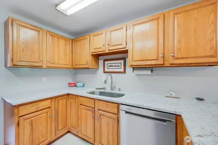 Plentiful wood cabinets, a new granite counter top, new sink and newer dishwasher makes this kitchen a happy place.