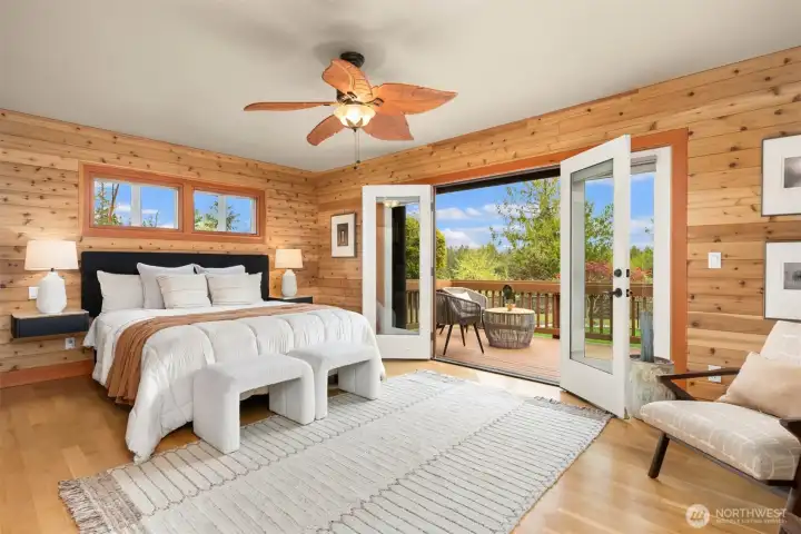 The primary is spacious yet cozy, with east-facing doors to a sunny part of the deck to get your morning light. The 5-piece bath and walk-in closet are near the entry door just behind the photographer in this photo.