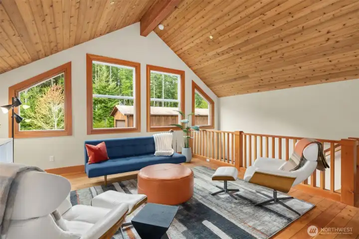 The loft’s west-facing windows frame evergreens and specimen trees.