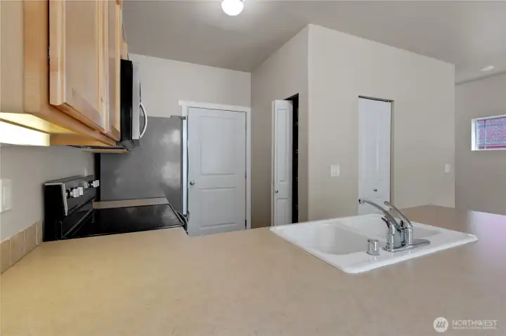 Kitchen with stainless steel appliances, maple cabinetry, and tile backsplash, featuring an eating bar, pantry storage, and convenient access to the garage.