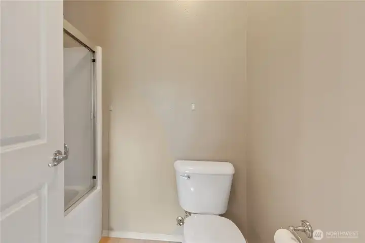 Primary bathroom with a tub/shower combination and toilet, offering practical everyday functionality in a private suite setting.