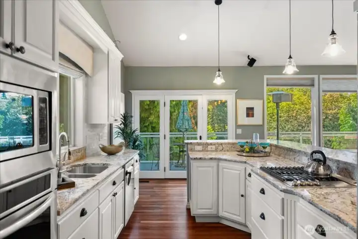 The beautifully updated kitchen features granite  countertops, white cabinetry, stainless steel appliances, convenient pull-out storage, and elegant pendant lighting over the breakfast bar. Large windows frame picturesque views of the lake, bringing natural beauty indoors.