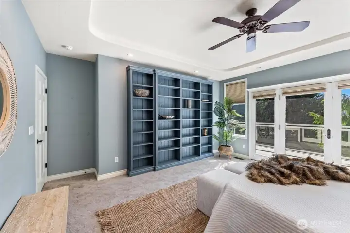 Expansive main floor primary suite offers a private retreat with decorative built-ins graceful coved ceiling and newly installed carpet. French doors open to the deck to take in the serene lake view.