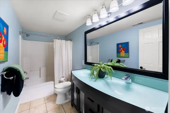 The lower level full bath is beautifully updated and features a stunning ebony vanity complemented by a matching mirror and striking glass vessel sink. Tile flooring adds style and durability.