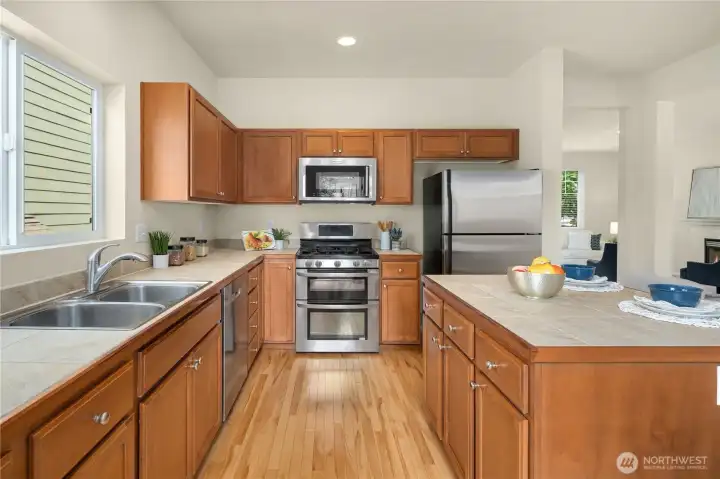 chef's kitchen with sleek stainless steel appliances, a center island, hardwood flooring
