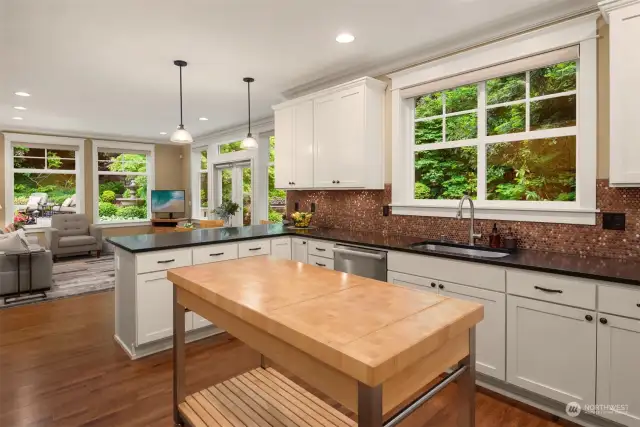 Chef's kitchen has Boos Island (stays with the home), matte black granite counters, custom cabinets, stainless steel appliances, wine fridge, breakfast bar and gorgeous view of the lush back yard.