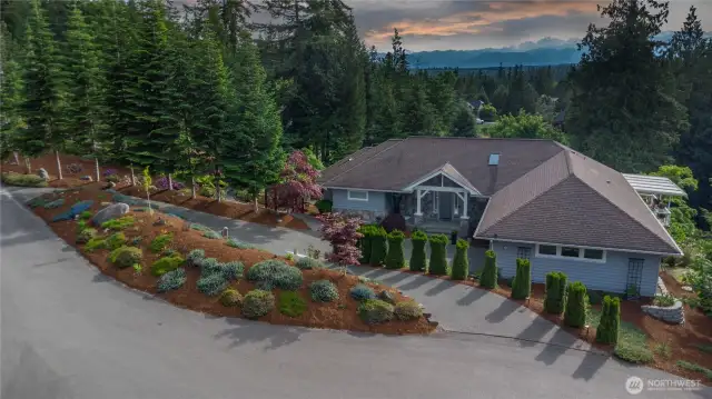 Located on 1.26 acres, this stunning home is on a cul-de-sac in a gorgeous neighborhood. West-facing views of the Olympic Mountains peak out above the clouds. Note the circular driveway for ease of parking.