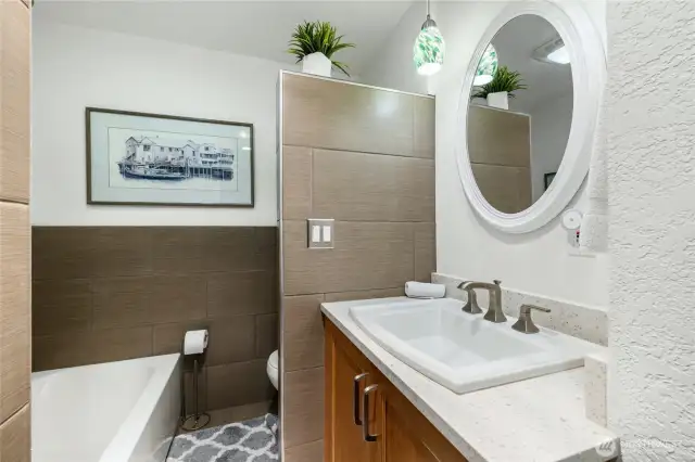 The primary bath features a vanity with quartz countertops, a soaking tub, and a separate shower.