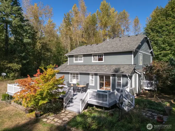 Welcome home. Dappled sunlight filters through the trees and across the wraparound deck—the perfect place to unwind as summer evenings stretch long into golden hour.