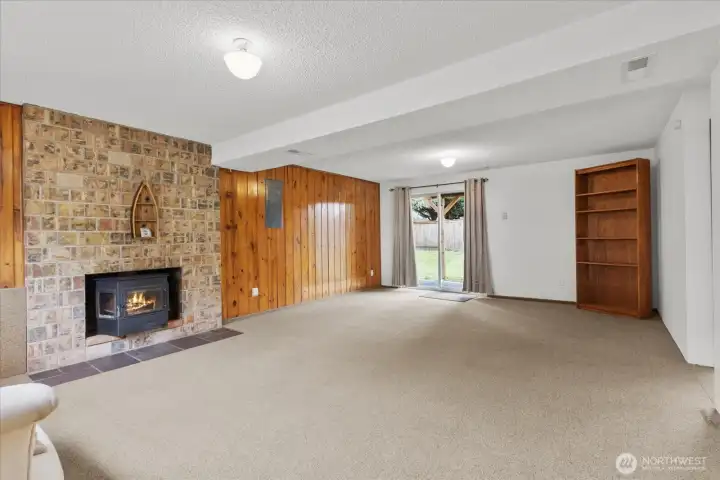 Lower-level rec room with masonry fireplace and backyard access.