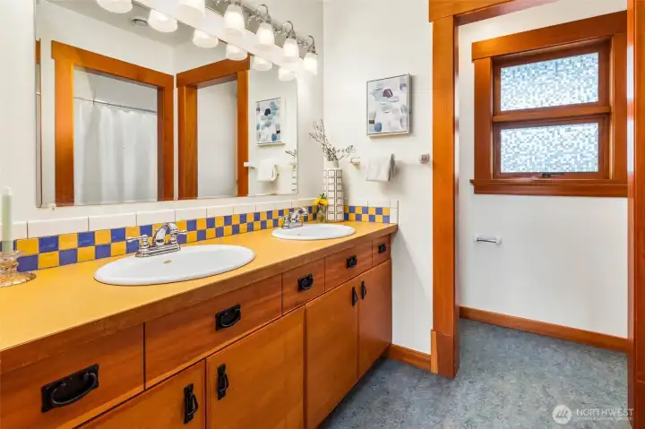 Full bath with dual sinks and colorful tile accents