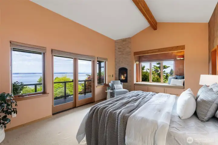 Primary bedroom with propane fireplace looking out to the water and moountains