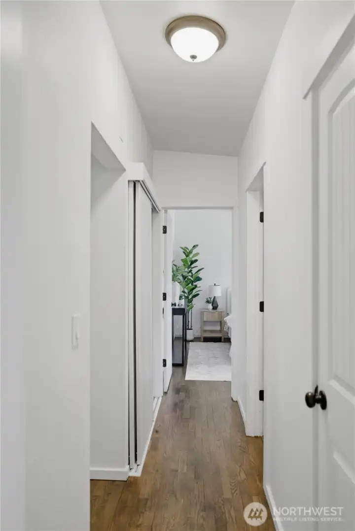 Hall looking from bedroom #2 into bedroom #1. Hallway also features a coat closet, full bathroom and utility closet with stackable washer/dryer.
