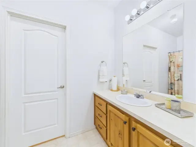 Your guest will like the nicely laid out guest bathroom with its wood cabinets and light counters.