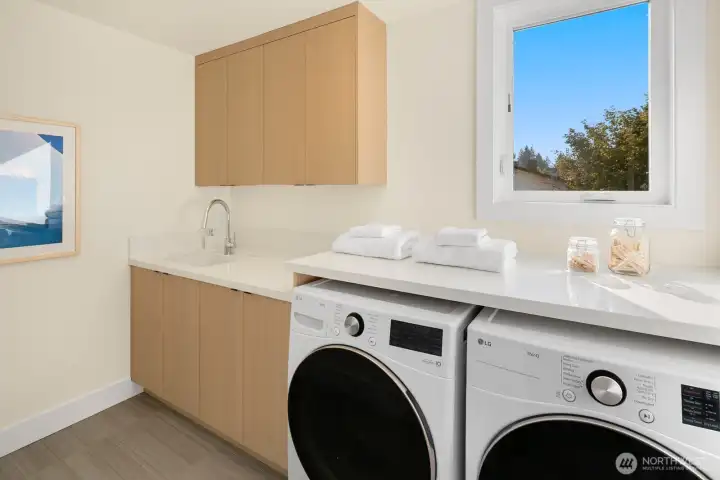 This is a laundry room with full-sized side-by-side washer and dryer and utility sink.
