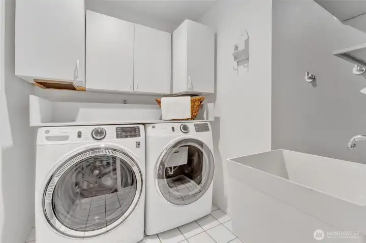 Laundry room offers storage, utility sink and tiled floors