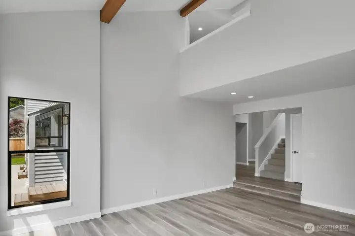 Soaring ceilings highlighted by wood beams create a striking architectural feature in the living room.