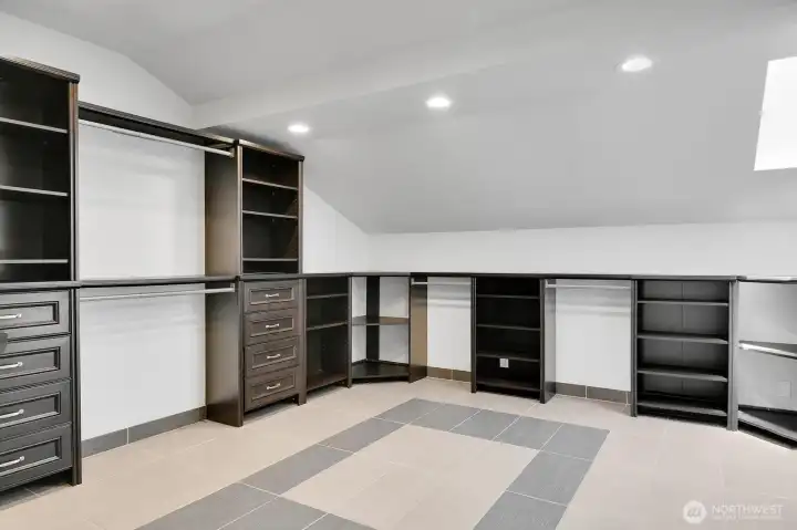 Massive vaulted Primary closet with heated tile floors and built ins! Go around the corner to the right and there's even MORE closet space with a skylight and more built ins!