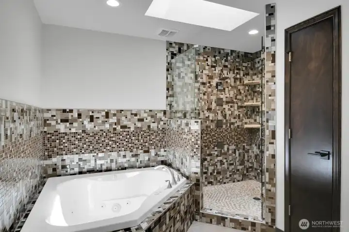 The Primary bath is like your own personal spa with a jetted tub, skylight, heated tile floors, and large walk-in shower with a rain shower head and several jets!