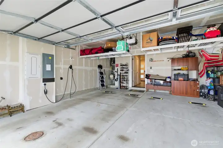 Two-car garage is fully equipped with a smart garage door opener, EV charger, and overhead storage