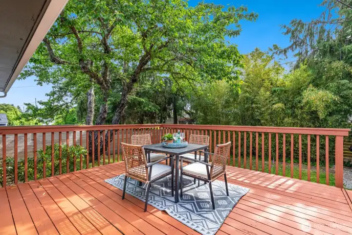 Large deck overlooks lush landscaping with mature trees.