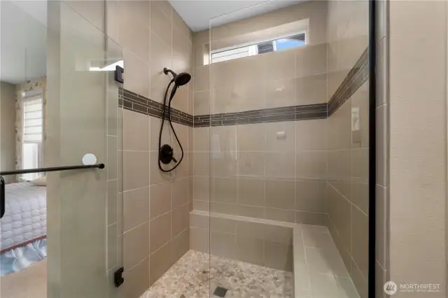 Fully tiled shower with a bench and a convenient niche.