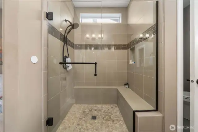 Fully tiled shower with a bench and a convenient niche.