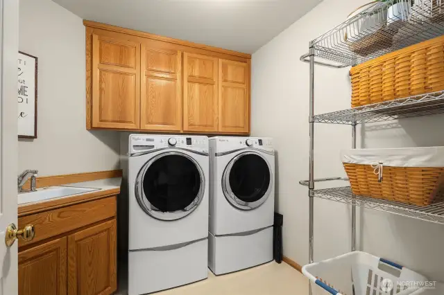 The large laundry room features a utility sink and storage cabinets.