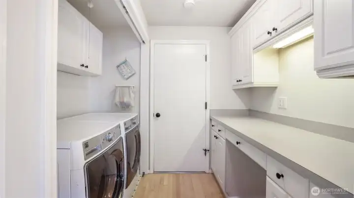 Spacious laundry room with built-in cabinets and folding counter.