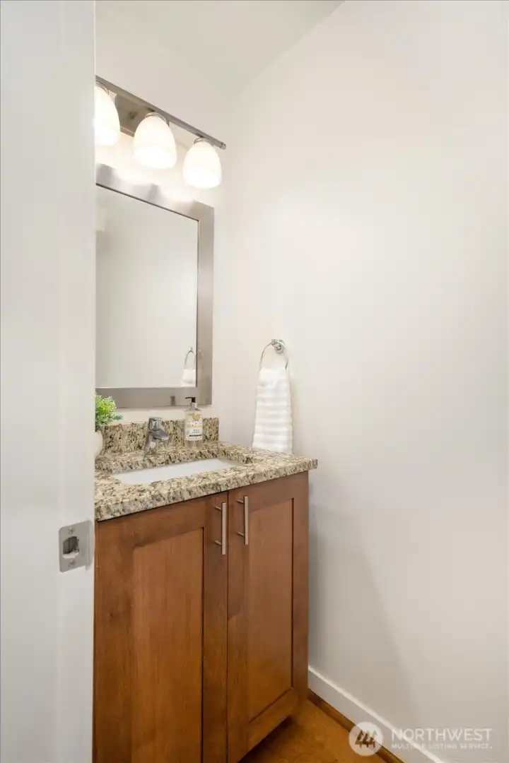 Main-level Powder Bath offers warm wood cabinets for storage.
