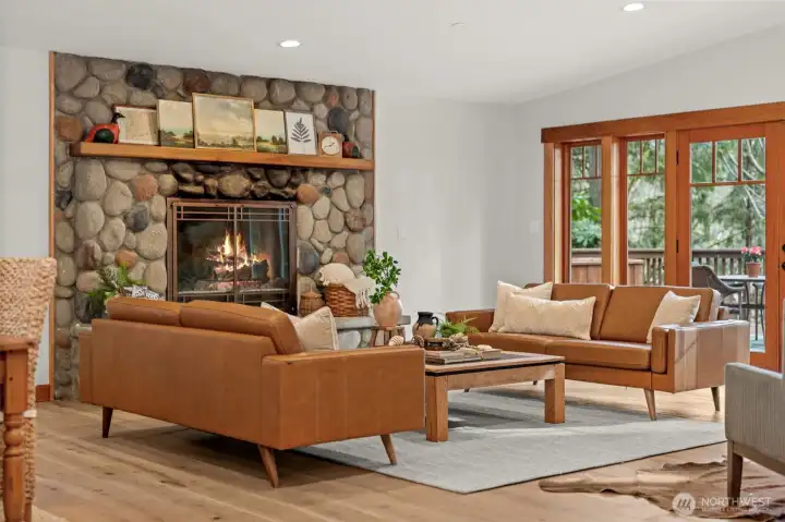 Living room with stone fireplace, hardwood floors, and natural light