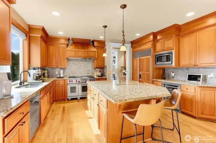 Impressive granite counters and tile backsplash. Wine/beverage fridge, microwave, stainless steel appliances and gourmet Wolf 48" gas range with hood.