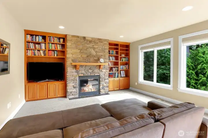 Beautiful stone gas fireplace with mantle and built in bookcase in the family room next to the chef's kitchen.