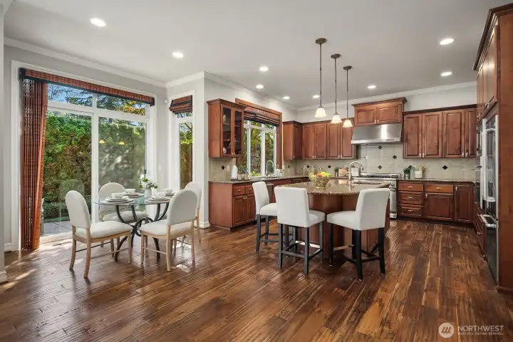 This stunning gourmet kitchen serves as the true heart of the home, featuring rich cabinetry, slab granite countertops, high-end appliances, and a generous center island with seating perfect for casual meals or entertaining. A sun-drenched breakfast nook with large windows overlooking the backyard adds a warm and inviting everyday dining space just steps away.