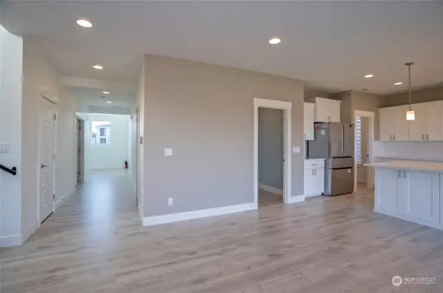 A view of the foyer hallway leading into the open-concept great room, with a centrally located door providing access to the garage.