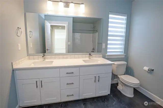 The full main guest bathroom features dual sinks and a shower/tub combination, perfectly blending style and functionality.