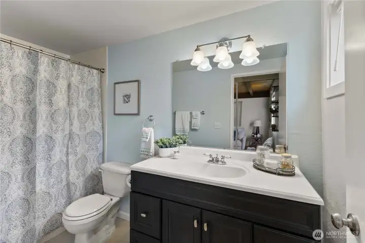 bathroom with modern updates, including sleek vanity and tiled surround.