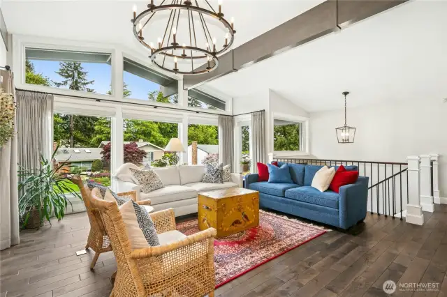 Spacious living room with large west-facing windows, custom drapes, and remote-controlled plantation blinds.