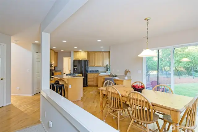 Expansive Chef's eat-in kitchen with maple cabinets and hardwood floors, large island, granite tile and tile countertops, newer appliances, 5-burner natural gas stove, wall oven and microwave, and a pantry.