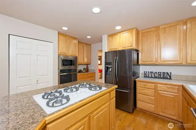 Kitchen island with granite tile countertops and 5-burner gas stove.