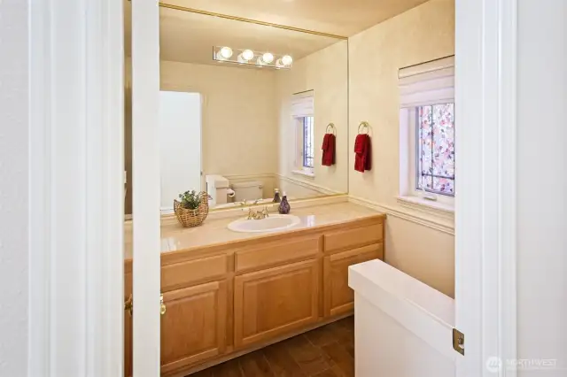 Powder room / half bath on the main floor with maple cabinets and tile flooring and countertops.