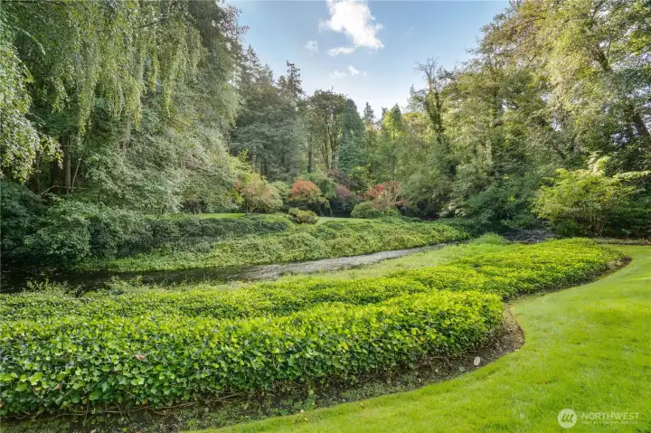Lawn next to the home with property extending past the lawn on the other side of the creek.