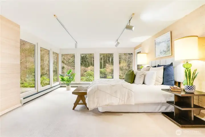 Primary suite with wraparound windows & door to balcony overlooking the creek & lawn.  Maples in the distance provide amazing fall color.