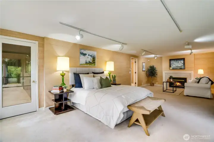 Master suite is expansive with gas fireplace in the seating area.   Door to balcony to left.  Grass cloth is on point for this home.